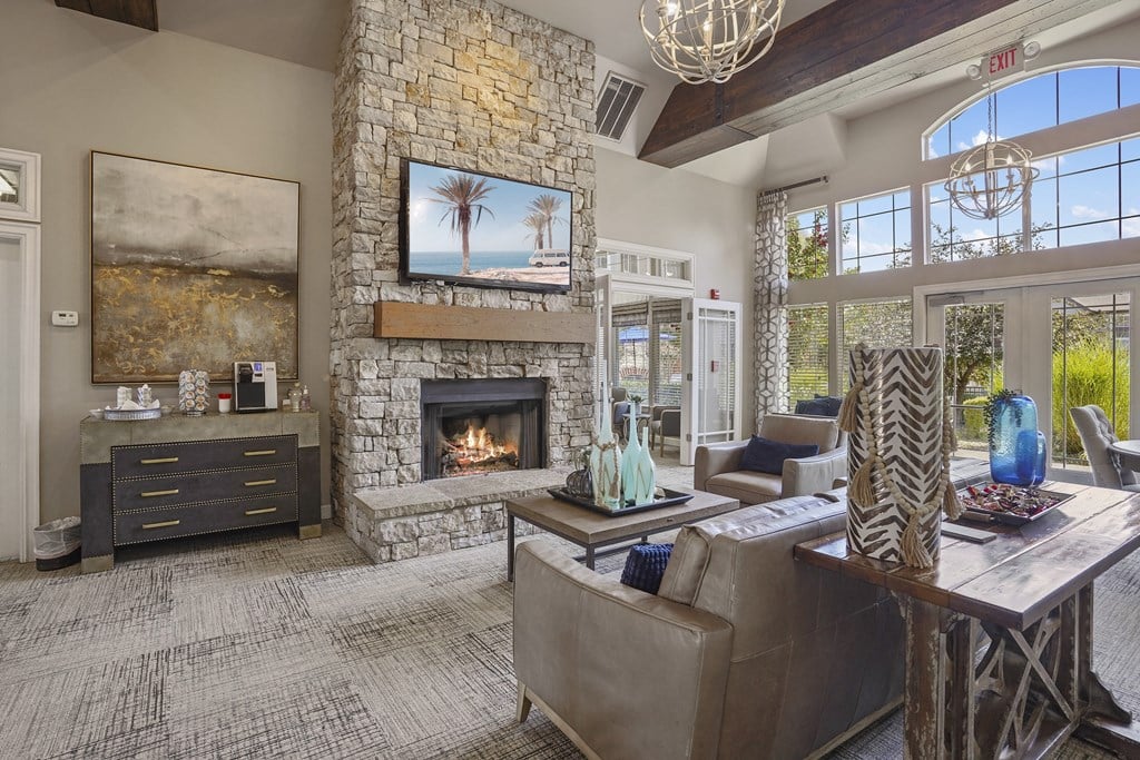 A living room with a stone fireplace and a painting of a beach scene on the wall.
