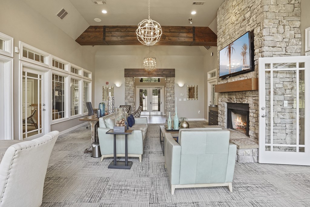 A living room with a stone fireplace and a television mounted above it.