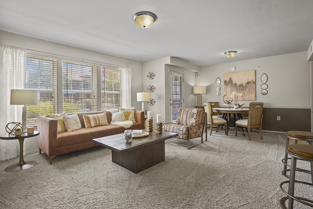 A living room with a brown couch and a grey carpet.
