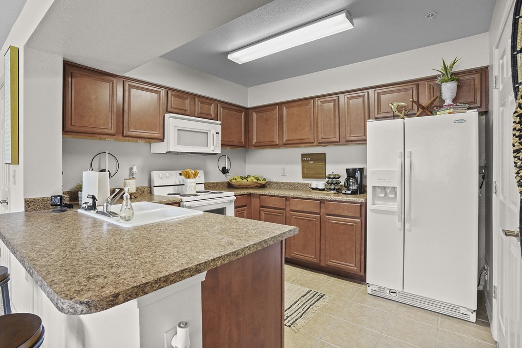 A kitchen with brown cabinets and a white fridge.