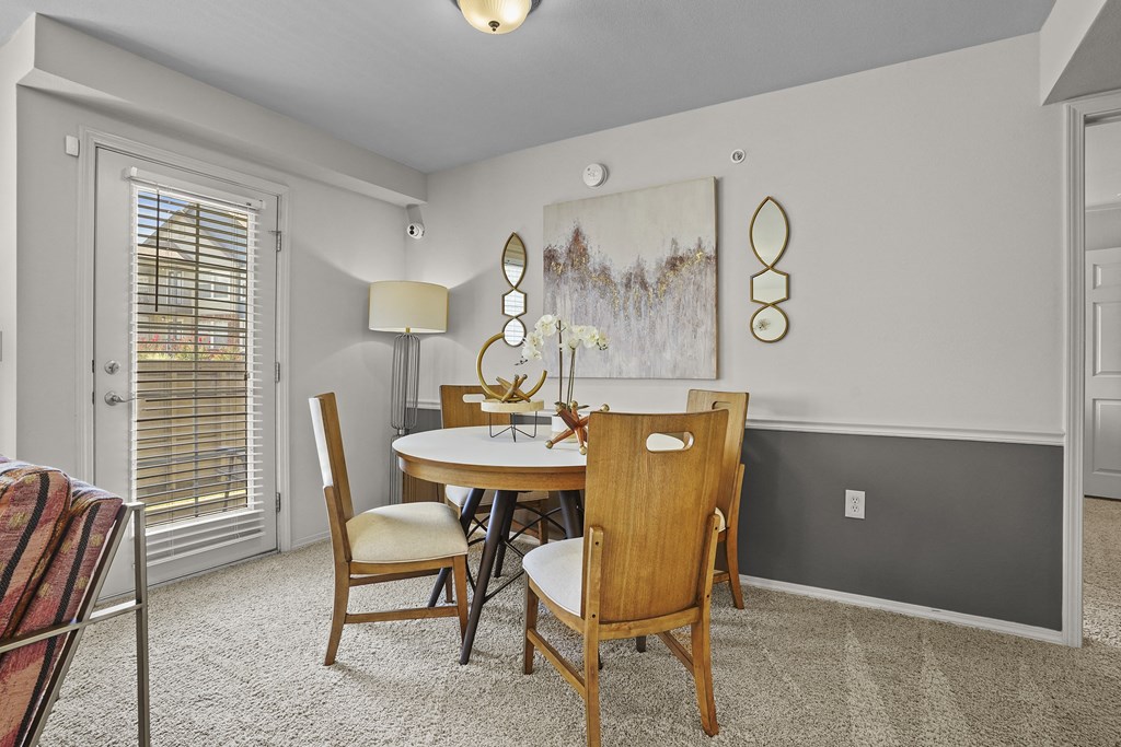 A dining room with a table set for two and a painting on the wall.