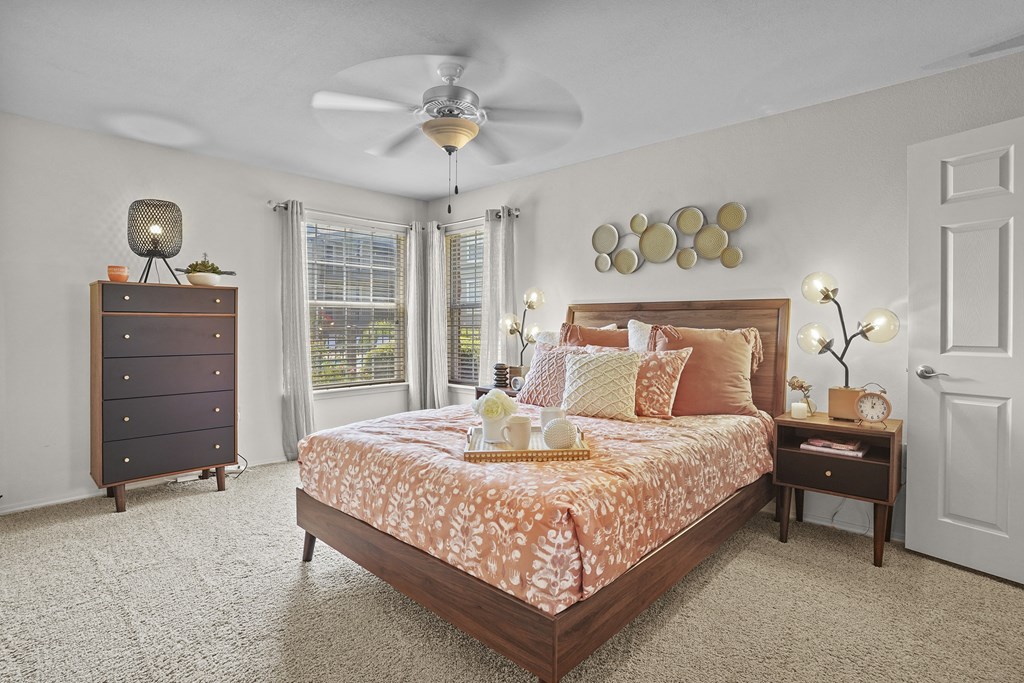 A bedroom with a bed, nightstand, and a ceiling fan.