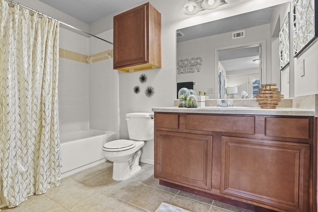 A bathroom with a toilet, sink, and shower curtain.