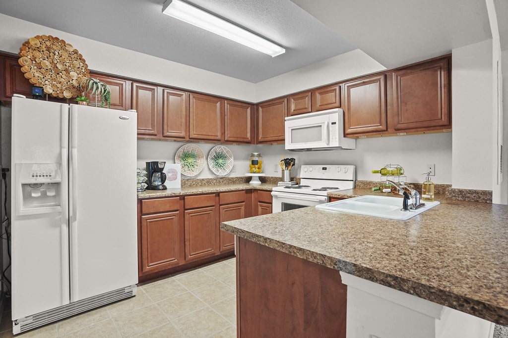 A kitchen with brown cabinets and a granite counter.