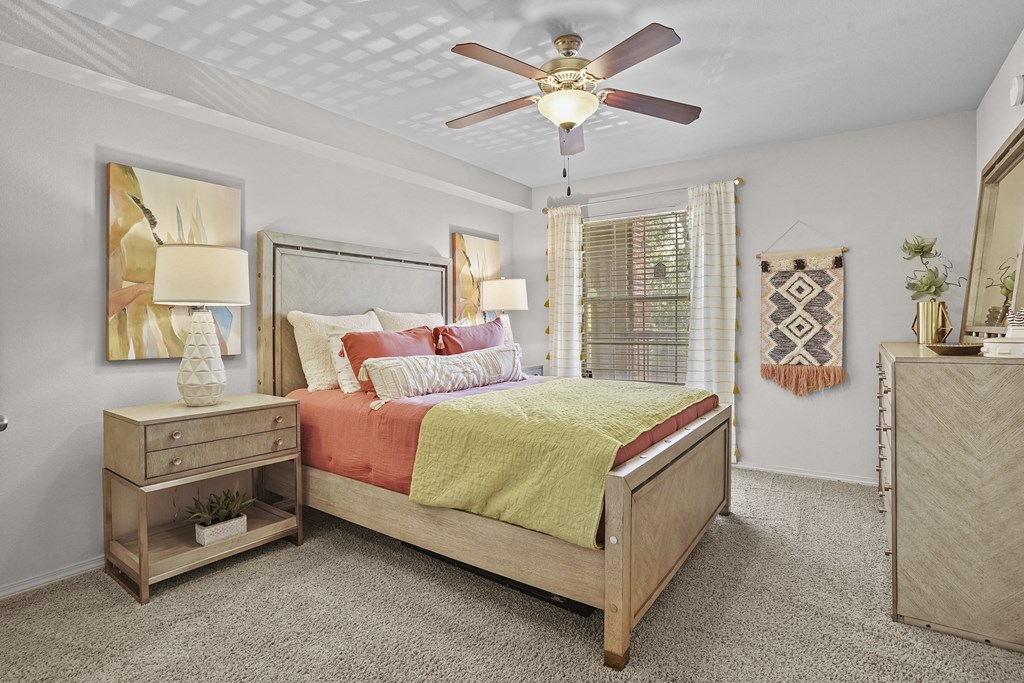A bedroom with a bed, nightstand, and a ceiling fan.