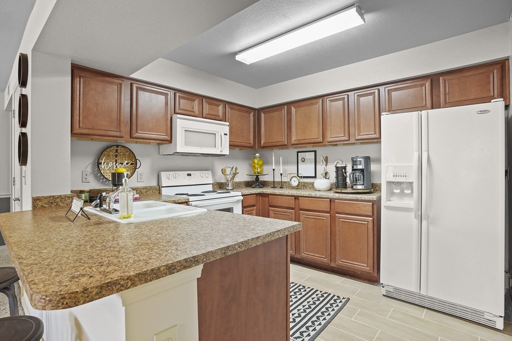 A kitchen with a granite countertop and white appliances.