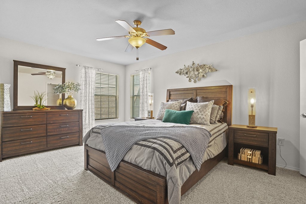 A bedroom with a bed, dresser, and ceiling fan.