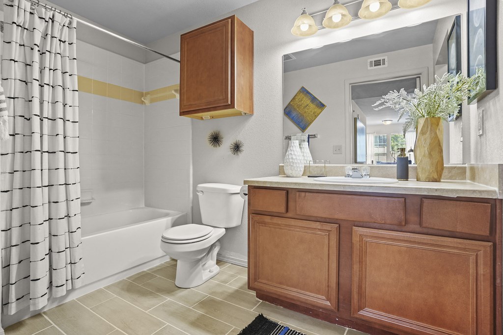 A bathroom with a white toilet and a wooden cabinet.