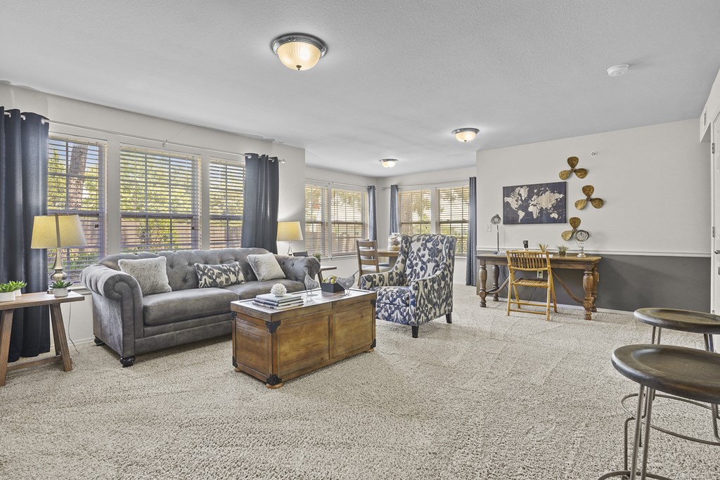 A living room with a grey couch, a wooden coffee table, and a chair with a floral pattern.