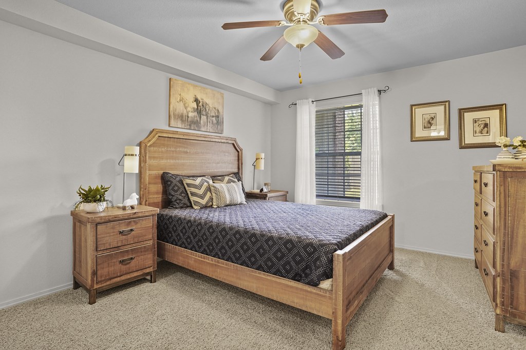 A bedroom with a bed, dresser, and a ceiling fan.