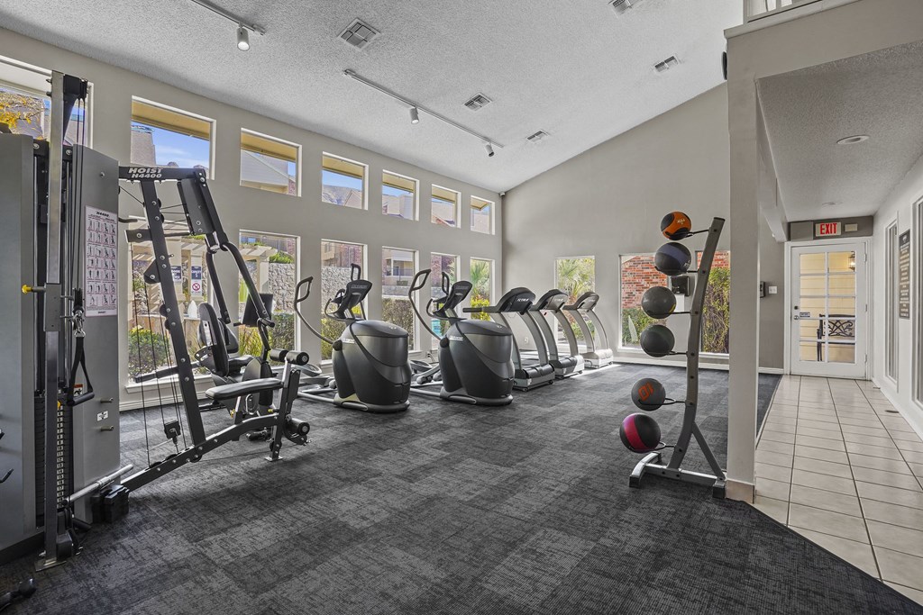 A gym with a variety of equipment including treadmills, weights, and exercise machines.