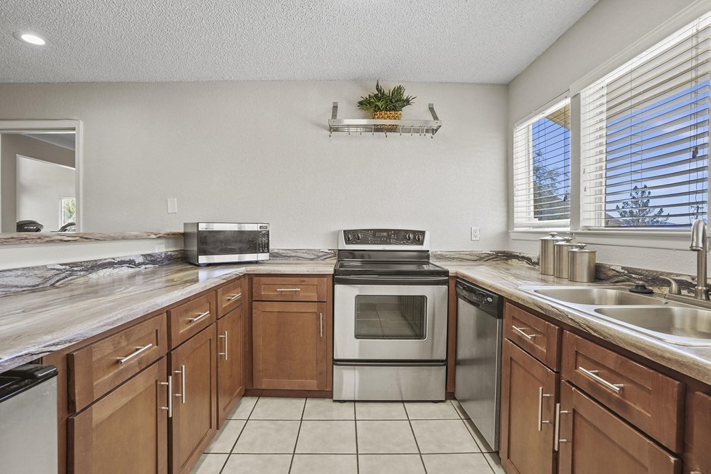 A kitchen with wooden cabinets and a marble countertop.