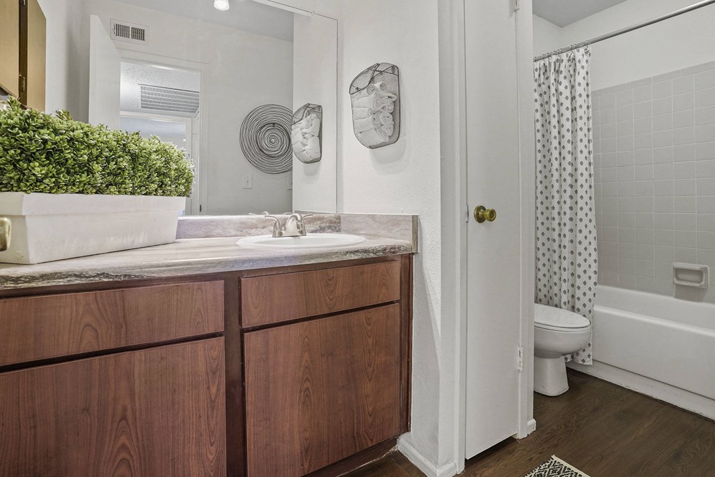A bathroom with a wooden vanity and a white bathtub.