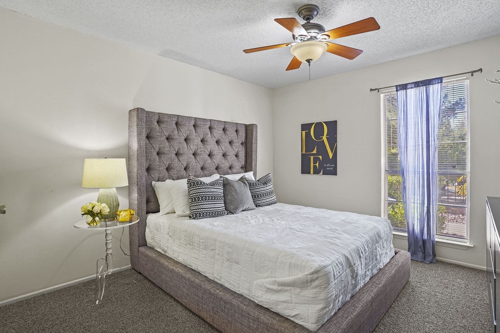 A bedroom with a large bed and a ceiling fan.