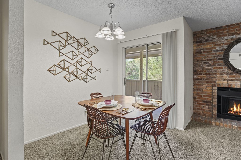 A dining room with a brick fireplace and a table set for two.