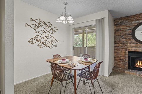 A dining room with a brick fireplace and a table set for two.