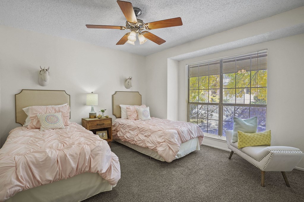 A bedroom with two beds and a ceiling fan.