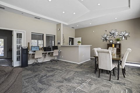 A room with a grey carpet and a dining table with chairs.