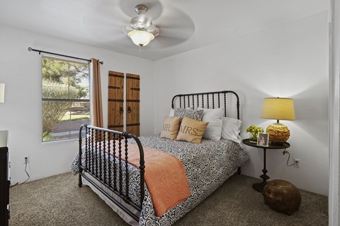 A bedroom with a bed, a ceiling fan, and a window with blinds.