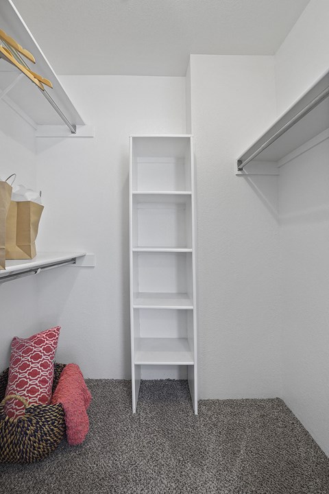 A white shelf unit with a pillow and a bag on the floor.