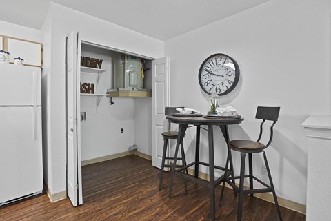A kitchen with a table and chairs and a clock on the wall.