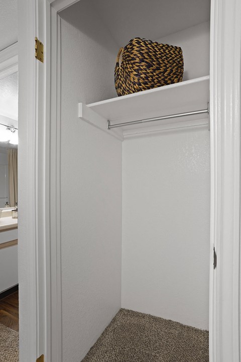 A white closet with a basket on the shelf.