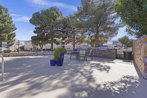 A courtyard with a bench, a tree, and a fence.