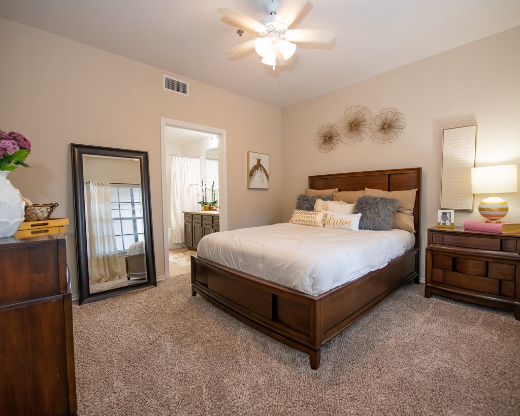 A bedroom with a large bed, a dresser, and a ceiling fan.