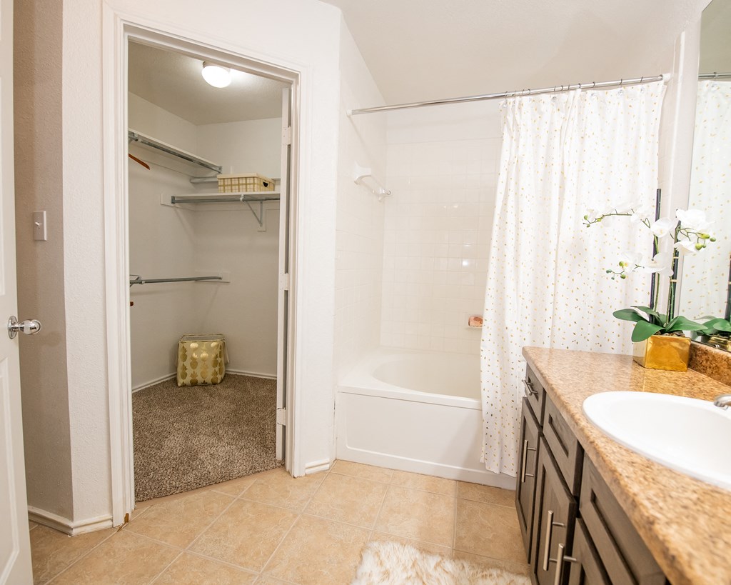 A bathroom with a white tub, sink, and shower curtain.