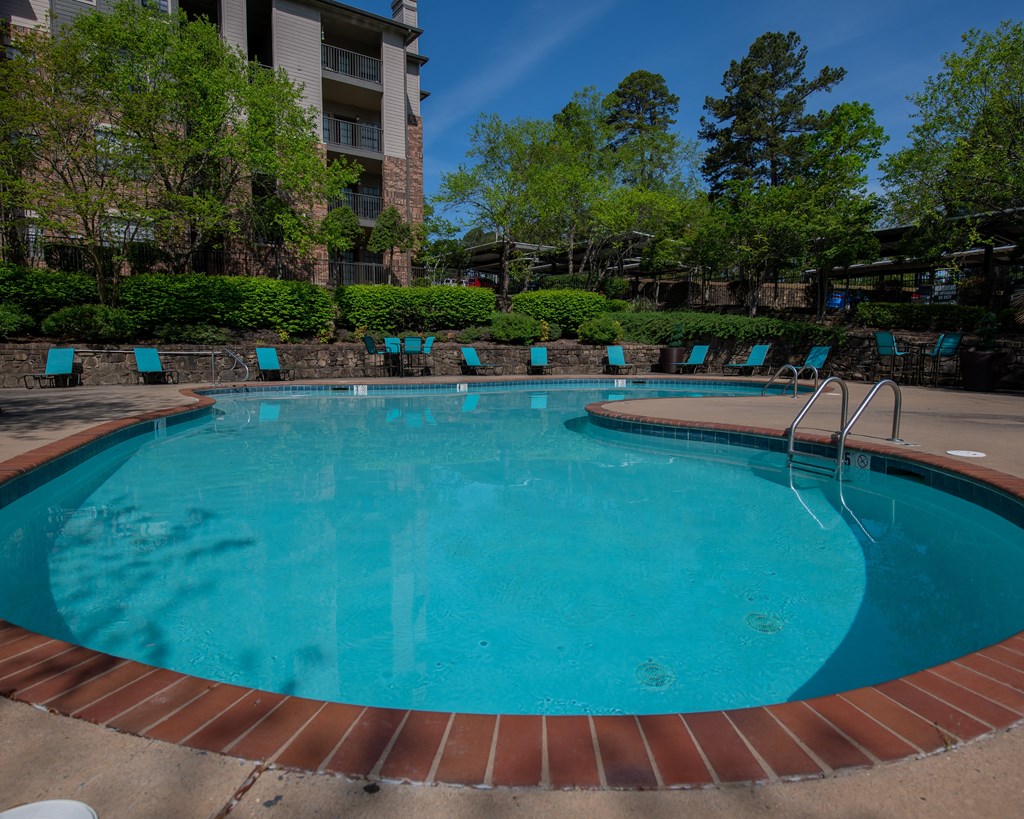 A round swimming pool with blue water and a brick border.