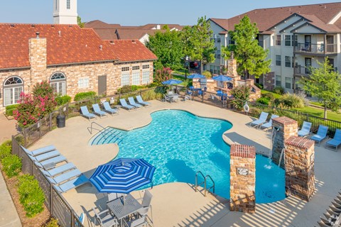 A pool surrounded by a stone wall and chairs.