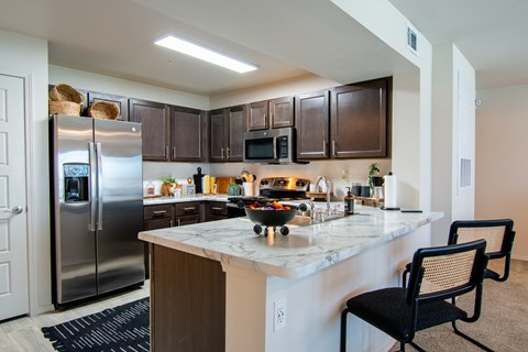 A kitchen with a marble countertop and a refrigerator.