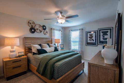 A bedroom with a bed, nightstand, and a ceiling fan.