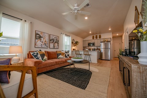 a living room with a brown couch and a ceiling fan