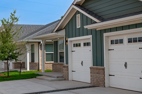 A house with a green roof and white garage doors.