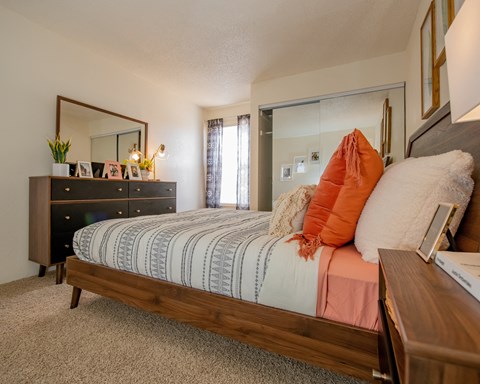 A bedroom with a bed, dresser, and mirror.