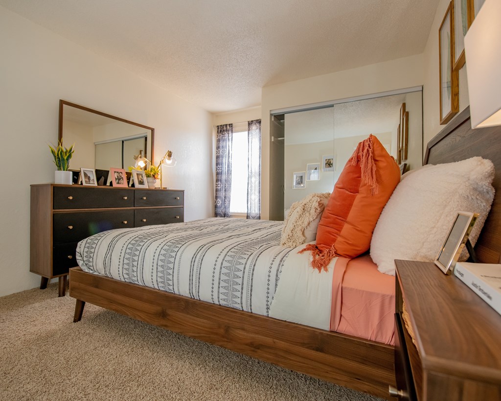 A bedroom with a bed, dresser, and mirror.