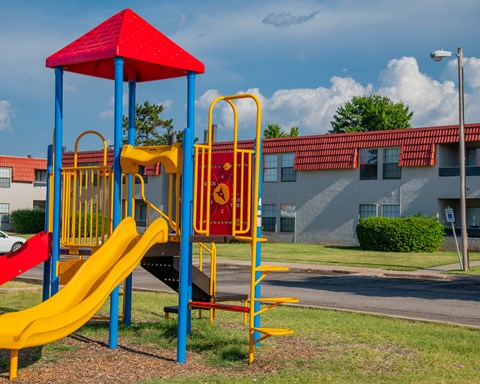 A playground with a red and yellow slide.