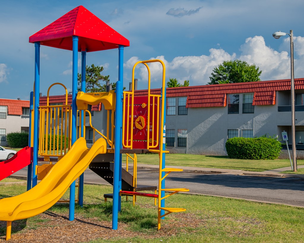 A playground with a red and yellow slide.