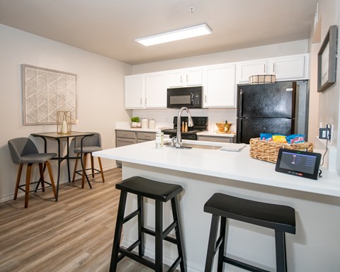 A kitchen with a black fridge and white countertops.