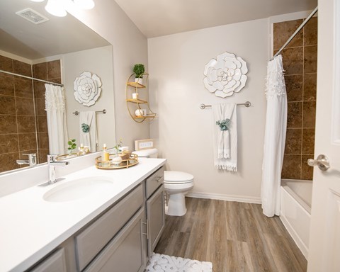 A white bathroom with a toilet, sink, and a white towel hanging on the door.