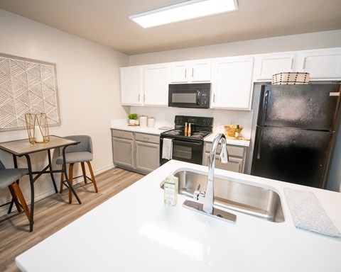 A kitchen with a black refrigerator, white countertops, and a skylight.