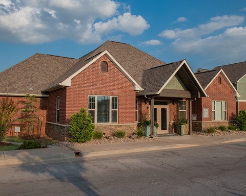 A red brick house with a brown roof and a green door.