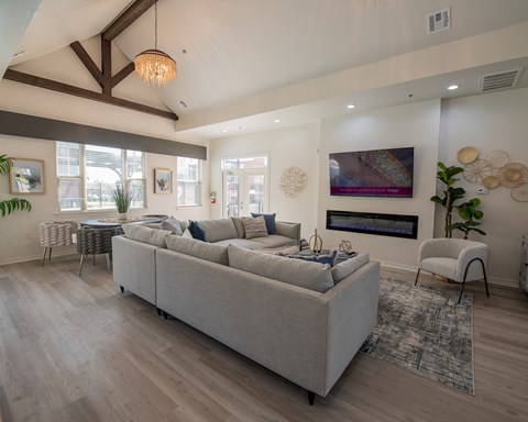 A modern living room with a grey sofa and a chandelier.