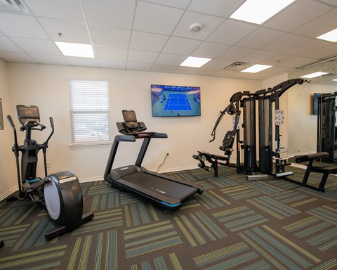 A gym with a treadmill, elliptical trainer, and other exercise equipment.