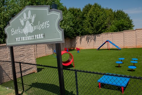 A sign that says "Barking Timbers Pet-Friendly Park" stands in front of a playground.