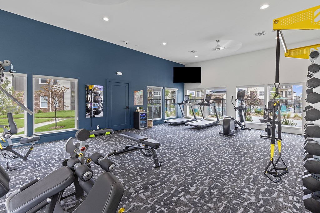 A gym with a variety of equipment including treadmills, weights, and exercise machines.