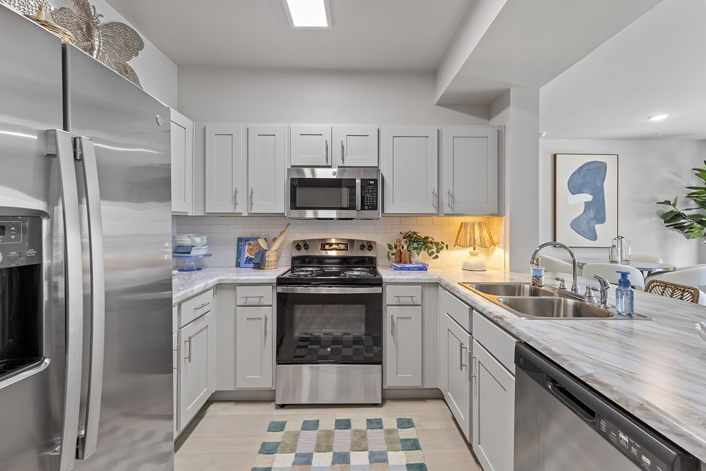A modern kitchen with stainless steel appliances and a checkered tile backsplash.