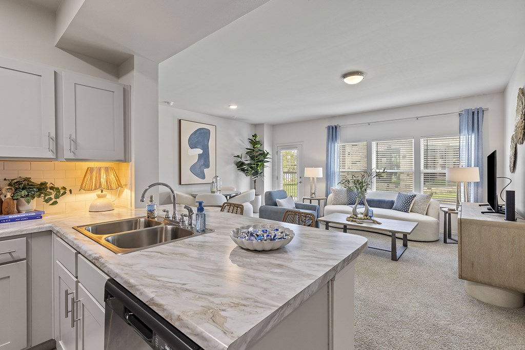 A modern kitchen with a marble countertop and a living area with a couch and a coffee table.