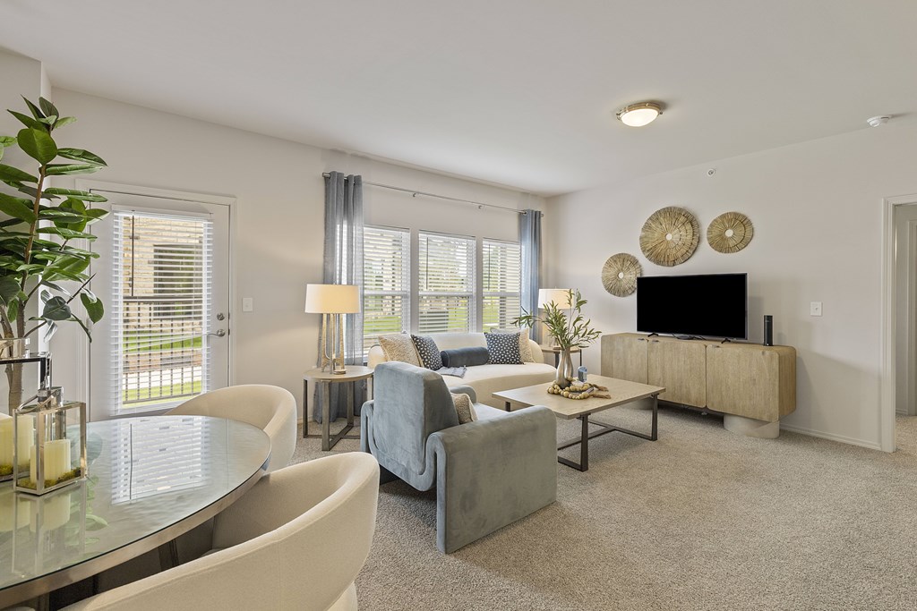 A living room with a grey couch, a glass table, and a television.